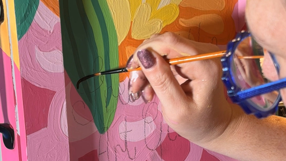 A detail photo of Hannah Pearlman painting the exterior of the Providence Free Little Art Gallery