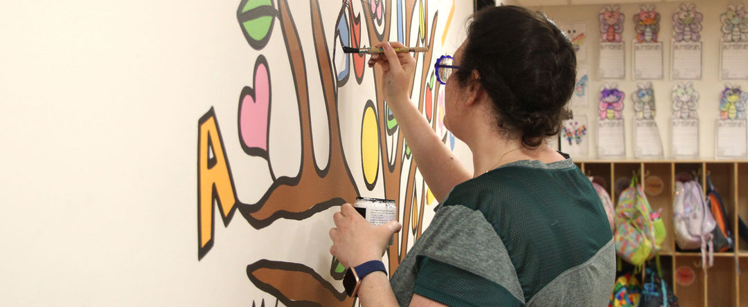 Hannah Pearlman painting a tree mural at an elementary school